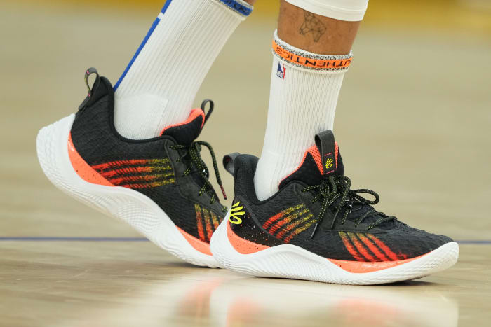 View of black, orange, and white Curry shoes.